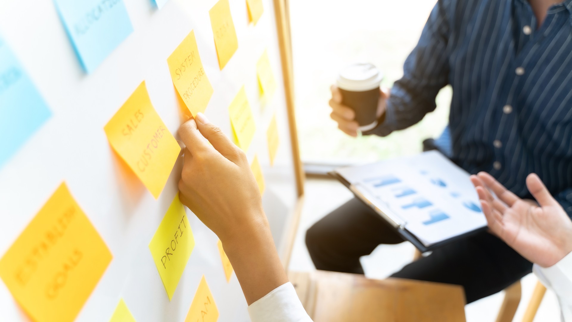 Team working in office putting sticky note on white board analyzing strategy of business.