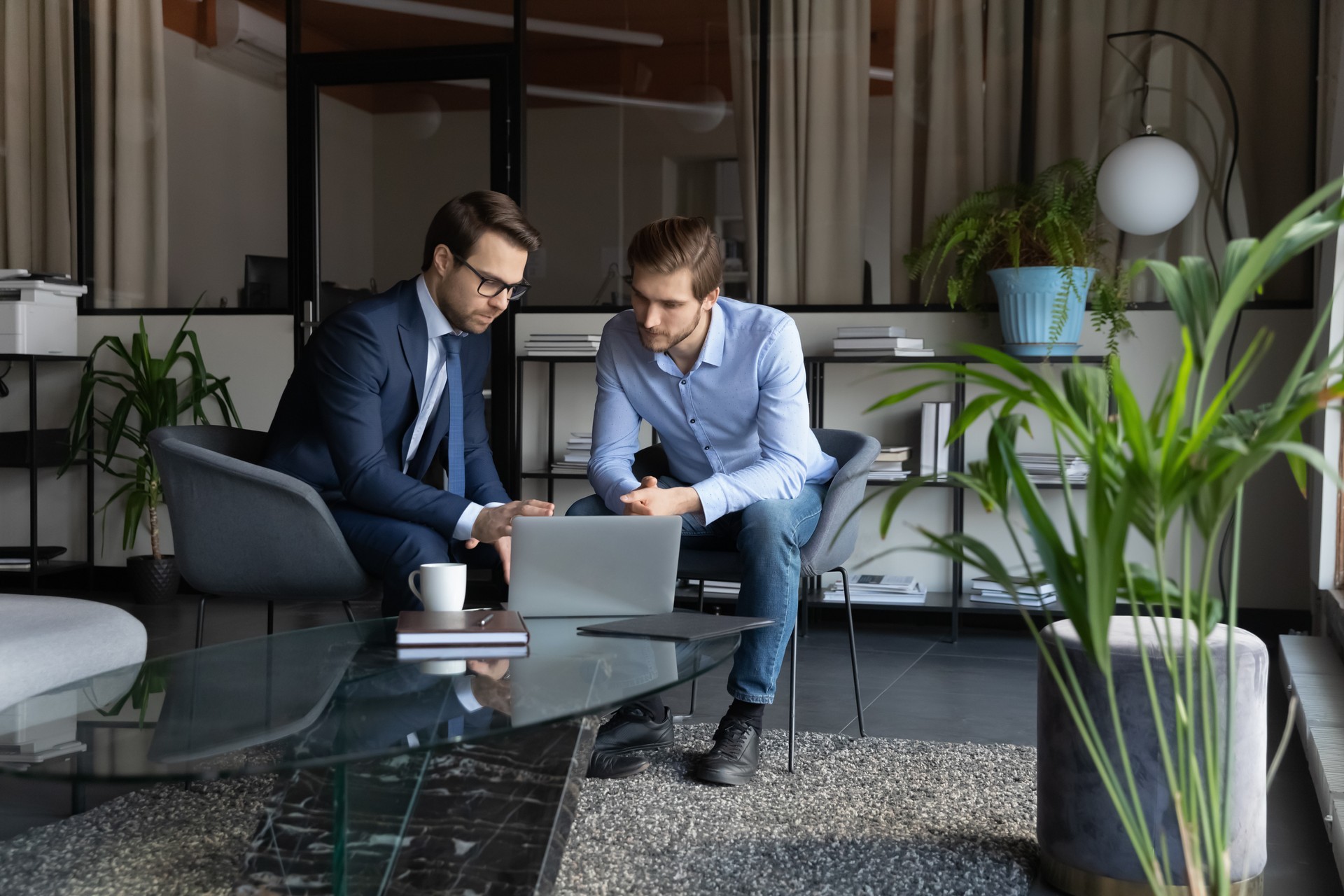 Colleagues using laptop, working on project in modern office together